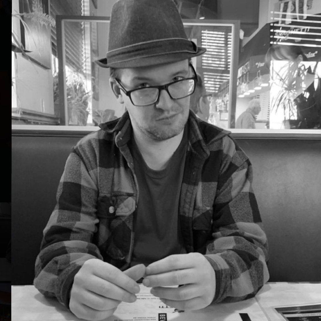 Ben Brunner in a fedora and plaid shirt, seated in a diner booth